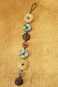 a long necklace with buttons and beads on a wooden surface, hanging from a cord