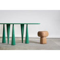 a green table and stool sitting next to each other on the floor in front of a white wall