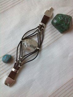 a piece of jewelry sitting on top of a table next to a green rock and two other items