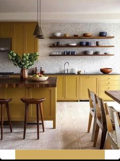 a kitchen with yellow cabinets and wooden stools