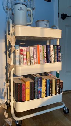 there is a book cart with many books on it in front of a door and a potted plant