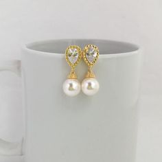 Simply Classic!!  I've created these charmings classic cubic zirconia and pearl bridal earrings in gold plated brass setting. Earrings feature teardrop clear cubic zirconia ear post and 10mm Swarovski pearl dangle drop. Total length of the earrings is 2.7 cms.For matching necklace click:https://www.etsy.com/listing/275221942/gold-pearl-and-crystal-bridal-necklace?ref=shop_home_active_15To browse my collection click :https://www.etsy.com/ shops/fantasycrystals Classic Gold-plated Pearl Drop Bridal Earrings, Classic Gold Plated Pearl Drop Bridal Earrings, Gold Pearl Crystal Earrings For Wedding, Yellow Gold Crystal Earrings For Wedding, Gold Cubic Zirconia Bridal Earrings, Yellow Gold Pearl Charm Bridal Earrings, Gold-plated Pearl Drop Bridal Earrings For Wedding, Gold Dangle Pearl Earrings With Cubic Zirconia, Yellow Gold Bridal Earrings With Pearl Charm