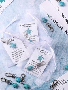 three little tags with charms attached to them sitting on a blue table cloth next to other items