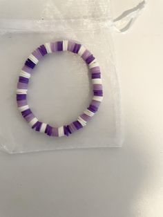 a purple and white beaded bracelet sitting on top of a plastic bag next to a string