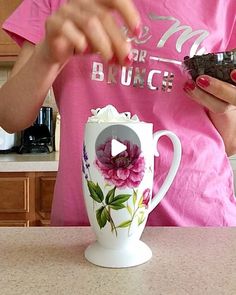 a woman is holding a piece of chocolate in her hand while standing next to a coffee cup