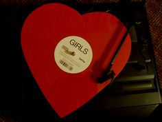 a red heart shaped record player with the word girls on it's disc cover