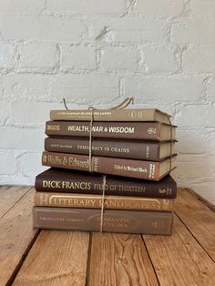 five books stacked on top of each other in front of a white brick wall