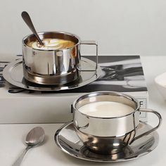 a silver cup and saucer sitting on top of a table next to a book