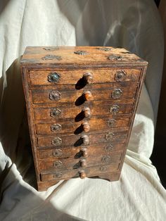 an old wooden drawer with knobs on it's sides sitting on a white sheet