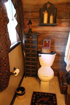 a white toilet sitting in a bathroom next to a wooden dresser and window with curtains