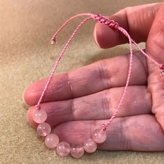 These soft pink rose quartz bracelets are fashionable and healing! Rugged and durable for 24/7 wear, but, still dainty, natural and feminine for her, this rose quartz bracelet is perfect for the whole family, gift giving. party favors, wedding parties and even for a gender reveal! This genuine gemstone bracelet features seven round 6mm rose quartz beads in the center of a comfy knotted bracelet. This trendy string bracelet is strung on durable high quality heavy braided nylon cord with a sliding Pink Adjustable Spiritual Braided Bracelet, Pink Hand-strung Braided Bracelets As Gift, Adjustable Pink Spiritual Friendship Bracelets, Pink Adjustable Spiritual Friendship Bracelets, Pink Hand Wrapped Braided Bracelets For Gift, Pink Hand Wrapped Braided Bracelet As Gift, Pink Hand Wrapped Braided Bracelet For Gift, Pink Beaded Bracelets With Adjustable Cord As Gift, Pink Adjustable Beaded Bracelets For Gifts