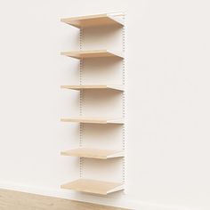 an empty shelf in the corner of a room with white walls and wood flooring