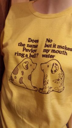 a person wearing a yellow shirt with two dogs on it's chest and the words does the name but it makes parvoy my mouth ring a bell water