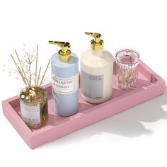 a pink tray with two bottles and candles on it