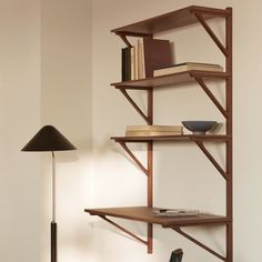 a wooden shelf with books on it next to a lamp