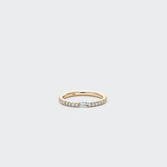 a yellow gold band with white stones on the side, set against a plain background