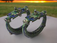 a couple Fine  Champleve Enamel  Anklets (Jhanhjar) Jhanjar anklets are large hollow rings which rattle when the wearer walks.The enamels on these jhanjhar anklets are champleve Punjab, Pakistan 19th century diameters at widest point: 13 cm, combined weight: 441g This spectacular  anklets is from the Punjab area of what is now Pakistan. Possibly such anklets were worn at weddings. They are of hollow sheet silver and have been chased and repoussed and then decorated with green and dark blue ename Bohemian Cutdana Bracelets As Gift, Bohemian Bracelets For Diwali Ceremonial, Traditional Handmade Bracelets For Diwali, Traditional Adjustable Green Cuff Bracelet, Traditional Green Adjustable Cuff Bracelet, Handmade Traditional Bracelets For Festivals, Traditional Green Bangle Cuff Bracelet, Traditional Hand Set Cuff Bracelet, Traditional Hand Set Bracelets For Ceremonial Occasions