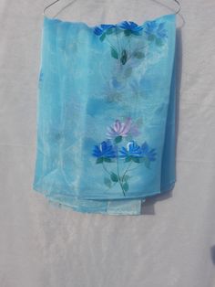 a blue scarf with flowers on it hanging from a hanger, against a white background