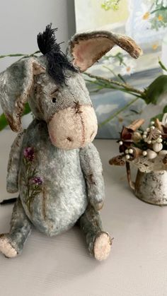 a stuffed animal sitting on top of a white table next to flowers and a potted plant