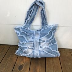 an old jean purse with holes and fraying on the inside, sitting on a wooden floor