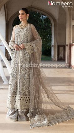 a woman in a white dress standing on a floor with an archway behind her and wearing a long veil over her head