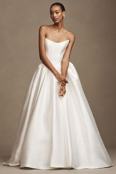 a woman in a white wedding dress posing for the camera with her hand on her hip