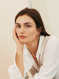 a woman is sitting down with her hand on her face and looking at the camera