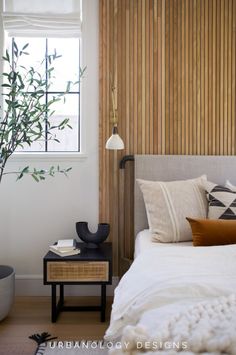 a white bed sitting under a window next to a wooden wall