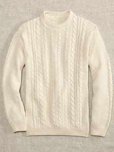 a white sweater is shown on a gray surface and it's made from wool