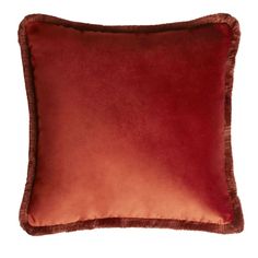 a red velvet pillow with fringe trim on the bottom and sides, sitting against a white background