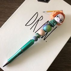 a green ballpoint pen sitting on top of a piece of paper with the letter d in it