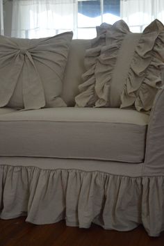 a white couch with ruffled pillows on it