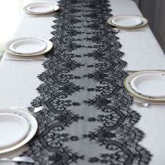 the table is set with white plates and black lace