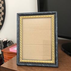 an old photo frame sitting on top of a wooden desk next to a computer monitor