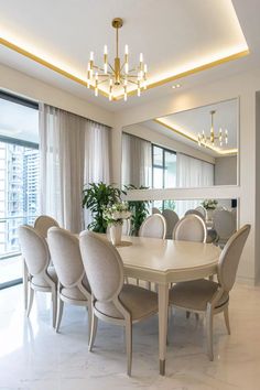 a dining room table and chairs in front of a large mirror with lights on it