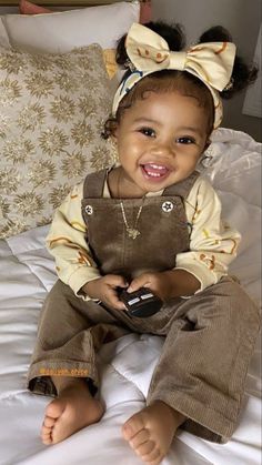 a smiling baby sitting on top of a bed