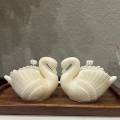 two white swans sitting on top of a wooden tray