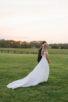 a bride and groom standing in the grass at sunset