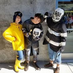 three people dressed in costumes standing next to each other on the side of a building