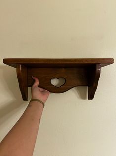 a person is holding up a shelf with a heart cut out on the top and bottom