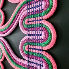 a colorful piece of art made out of crocheted yarn on a black surface