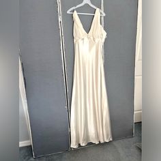 a white dress hanging on a hanger in front of a gray wall and door