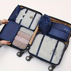 an open suitcase with clothes in it sitting on the floor next to someone's hand