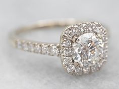 an engagement ring with a diamond center surrounded by small round brilliant cut pave diamonds