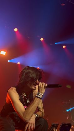 a man sitting on top of a stage holding a microphone in front of his face