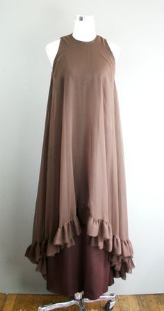 "This is a head-turner. It is a brown polyester sheath with a sheer chiffon overlay that features a high-low hemline. It is in excellent ready to wear condition. Estimated size S 34\" bust 28\" waist 38\" hip 54\" nape of neck to hem Purveyor's Note: We have searched far and wide, wrestled bears, braved the cold, traversed mountain ranges, fought pirates, swam with sharks and eaten at many a questionable road side taco stand to provide our customers with one of a kind vintage pieces. Know that w Ruffled Georgette Chiffon Dress For Party, Sheer Flowy Silk Chiffon Dresses, Flowy Silk Chiffon Dress, Sheer Chiffon Dress With Flowy Skirt, Chic Sheer Silk Chiffon Dress, Party Dresses With Georgette Overlay, Flowy Georgette Party Dress, Party Dresses In Georgette With Overlay, Party Georgette Dress With Overlay