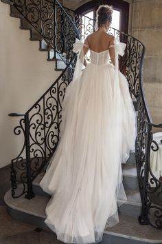 a woman in a wedding dress is walking down the stairs with her back to the camera