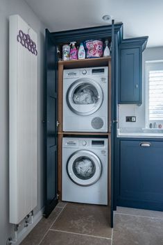 a washer and dryer in a small room with blue cabinets on the wall