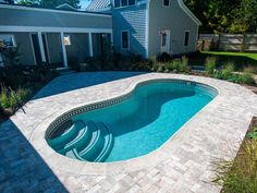 an empty swimming pool in the middle of a backyard with landscaping around it and brick pavers