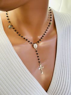 This is a stunning 14 karat gold filled charmed rosary inspired necklace. This necklace consist of 3.5 mm faceted onyx beads on 14k gold filled chain , four religious gold filled charms with a miraculous center and crucifix cross. This beautiful crucifix cross measures 28X 16 MM. Miraculous medal measures 16 X 13 MM and is double sided. The charms attached all are 14 karat gold filled. Tiny Saint Benedict medallion measures 10MM, our Lady of Guadalupe charm measures 9MM, pavé crystal Hamsa charm measures 11 MM and evil eye charm measures 11 X9MM. There is a spring clasp in back with a 2 inch adjustable length. Necklace on model is a 16-18 inch length. This is completely 14 karat gold filled.  Comes in a gift box ready to present. If you would like a different gemstone or crystal please sen